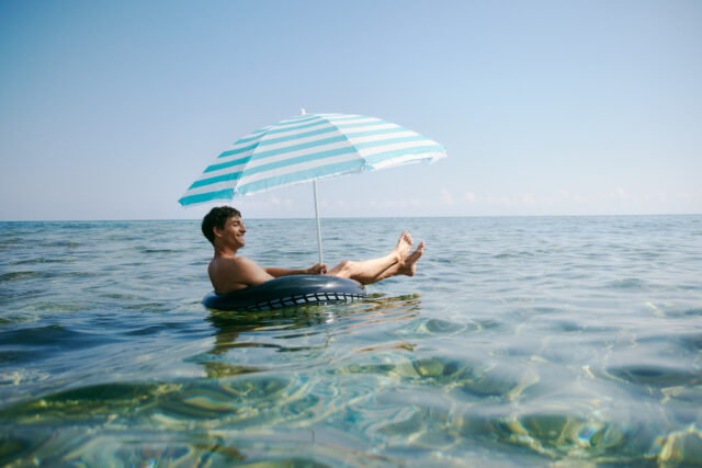 a man floating on a tube with an umbrella in the water