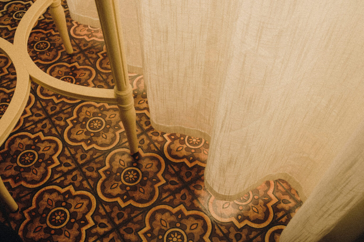 a white curtain on a tile floor