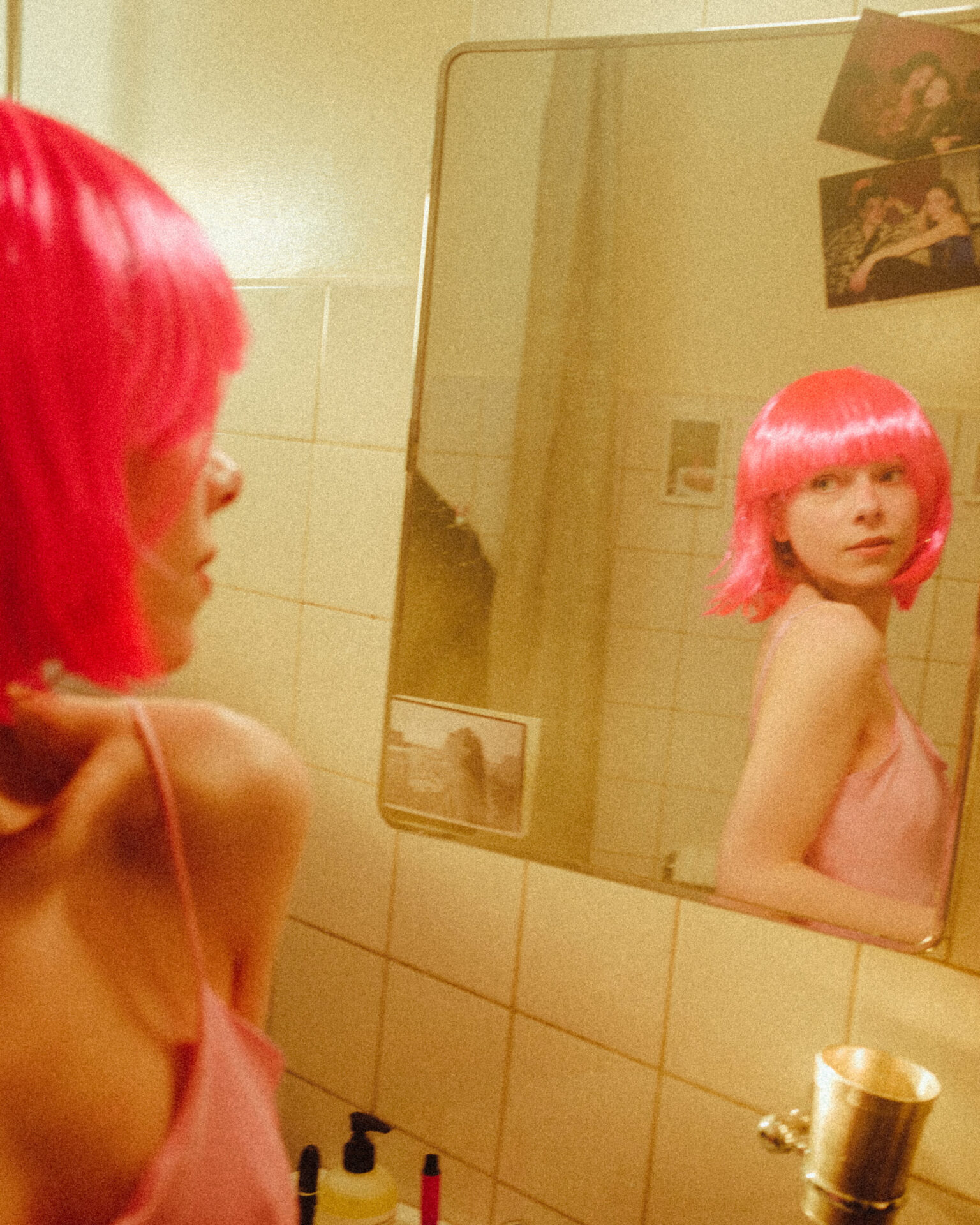 a woman with pink hair in a bathroom mirror