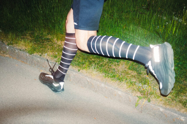 a person wearing black and white socks and running on a road
