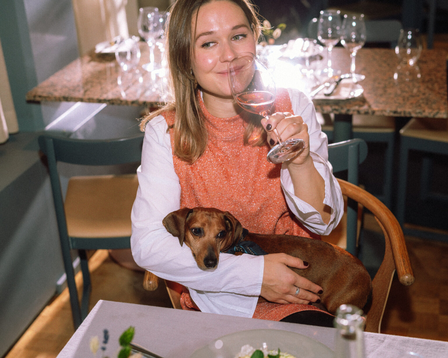 a woman holding a glass of wine and a dog