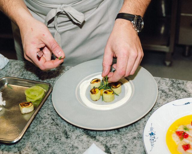 a person's hands putting food on a plate
