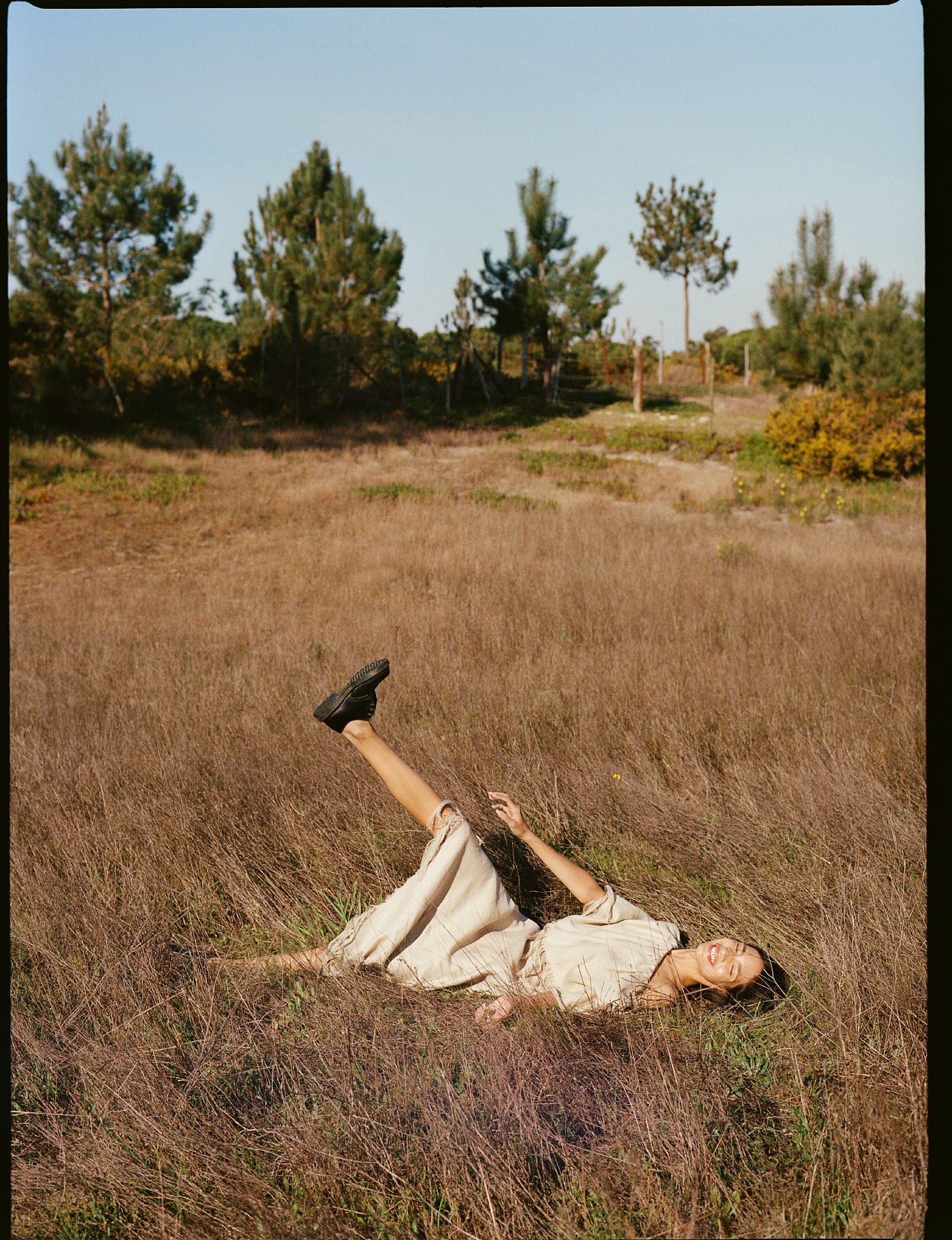 a woman lying in a field with her leg up