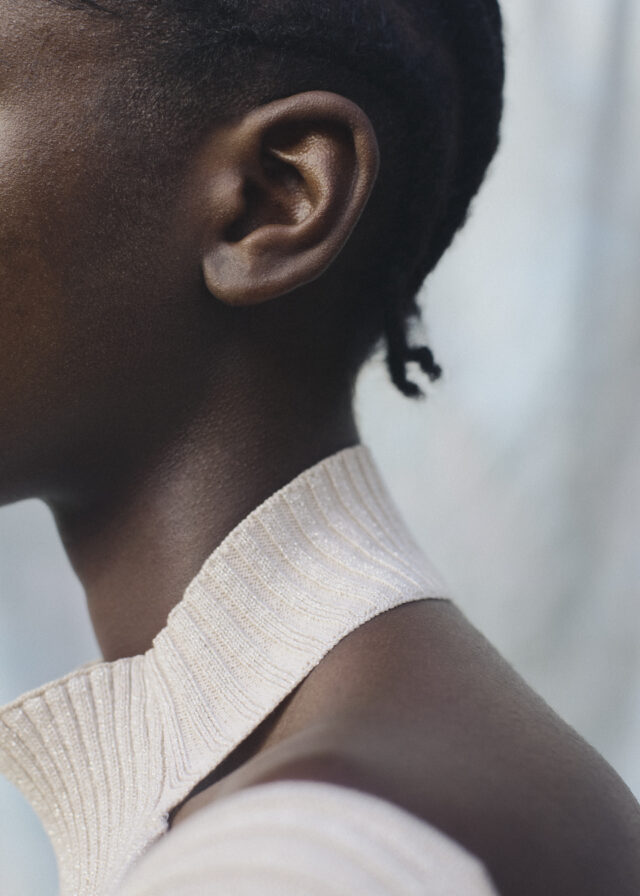 Close-up of a person's ear and shoulder in a light-colored sweater.