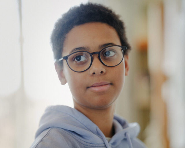 a boy wearing glasses and a hoodie