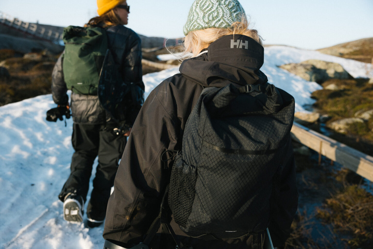 a woman in a hat and backpack walking in the snow