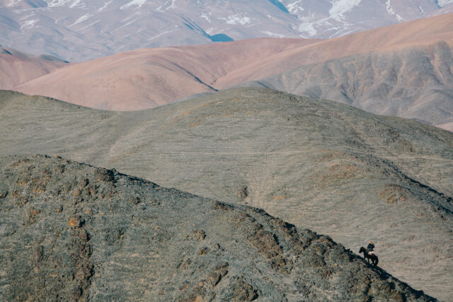 a person riding a horse on a rocky hill