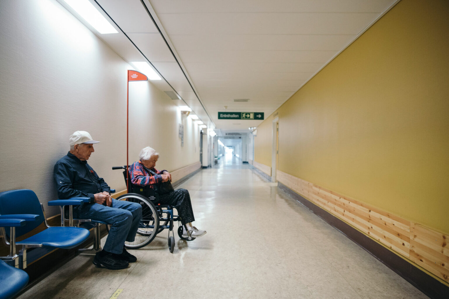 a man and woman sitting in wheelchairs in a hallway