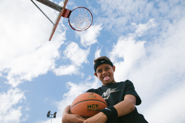 a boy holding a basketball and sticking his tongue out
