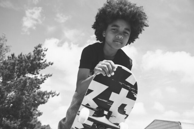 a boy with afro hair riding a skateboard