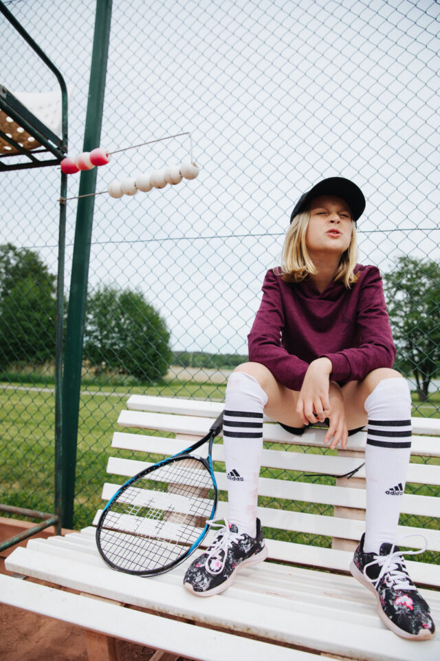 a girl sitting on a bench with a tennis racket