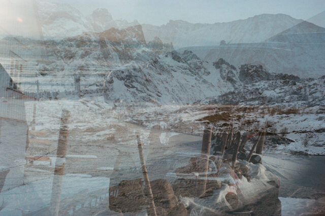 a snowy mountain landscape with a bridge and a road