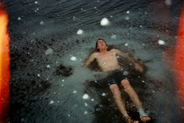 a man lying in water with snow falling