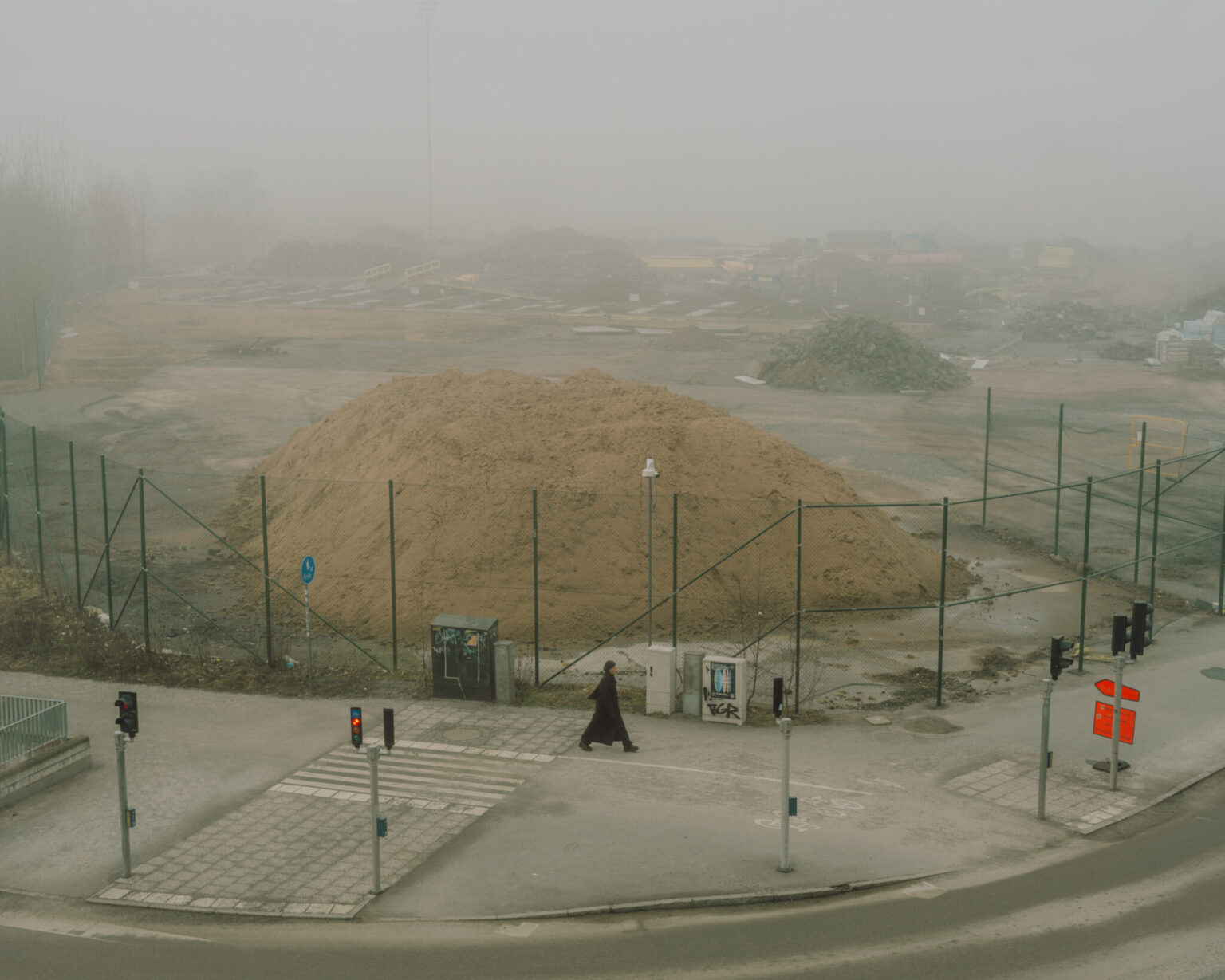 a person walking on a street with a pile of dirt in the background