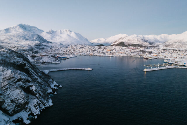 a body of water with snow covered mountains and a city