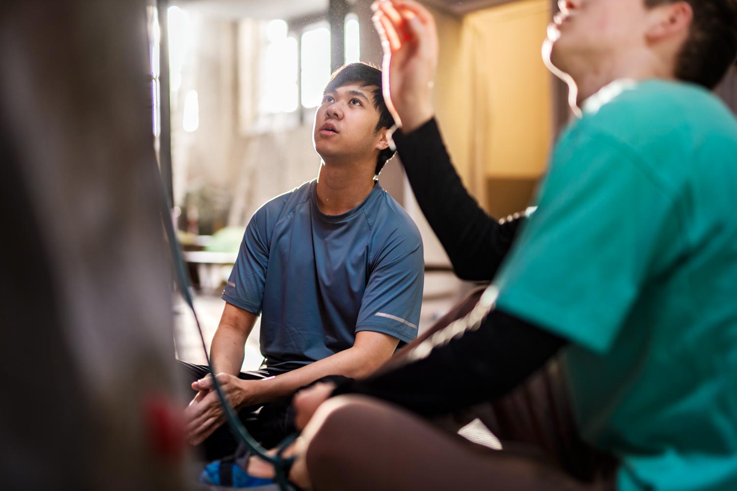 Två unga män sitter vid en klättervägg.