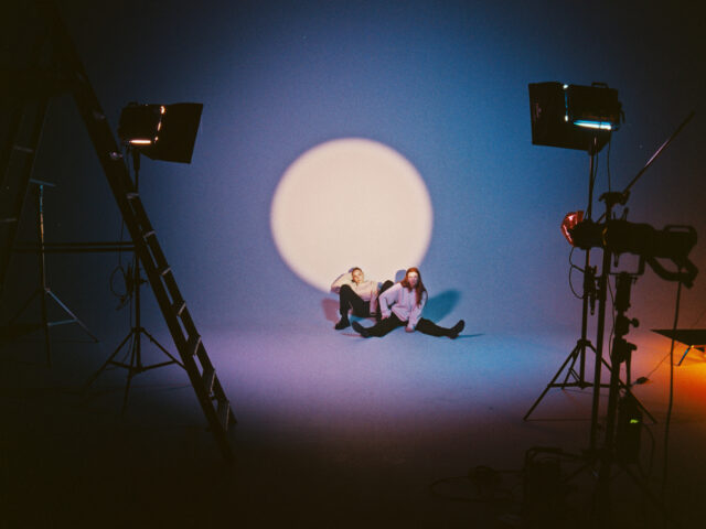 a man and woman sitting on the floor in front of a white circle