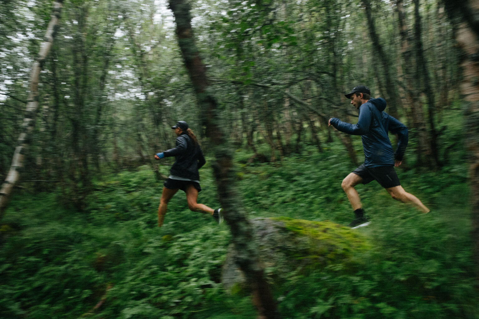 a man and woman running in the woods