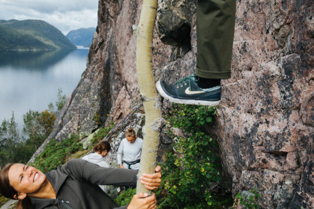 a person holding a tree with a person's foot on a rock