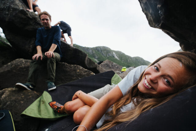 a woman lying on a blanket with people behind her