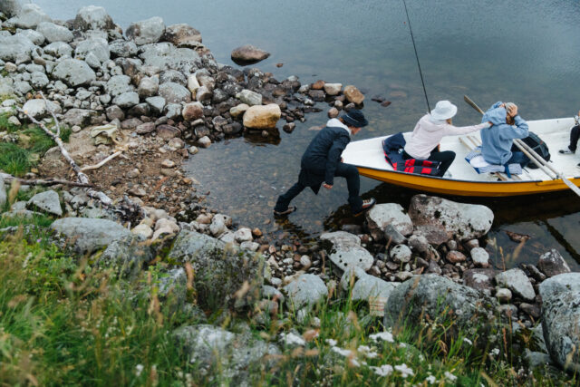 a man and woman in a boat on a rocky shore