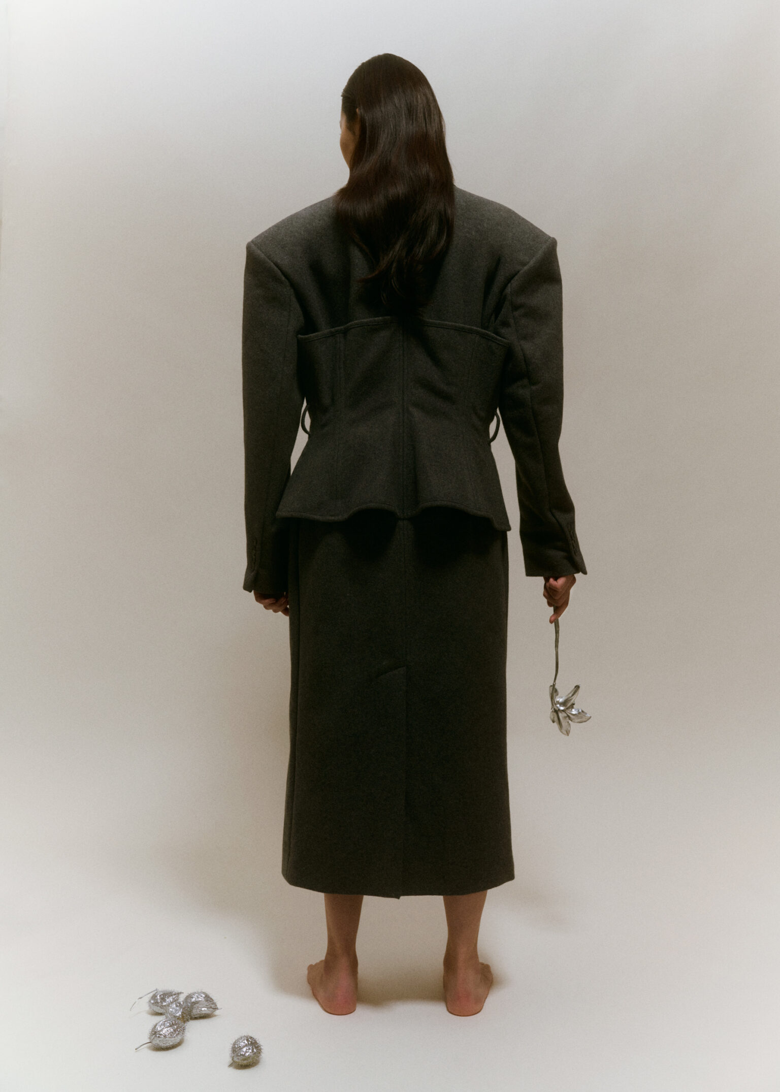 a woman in a long black coat holding a flower