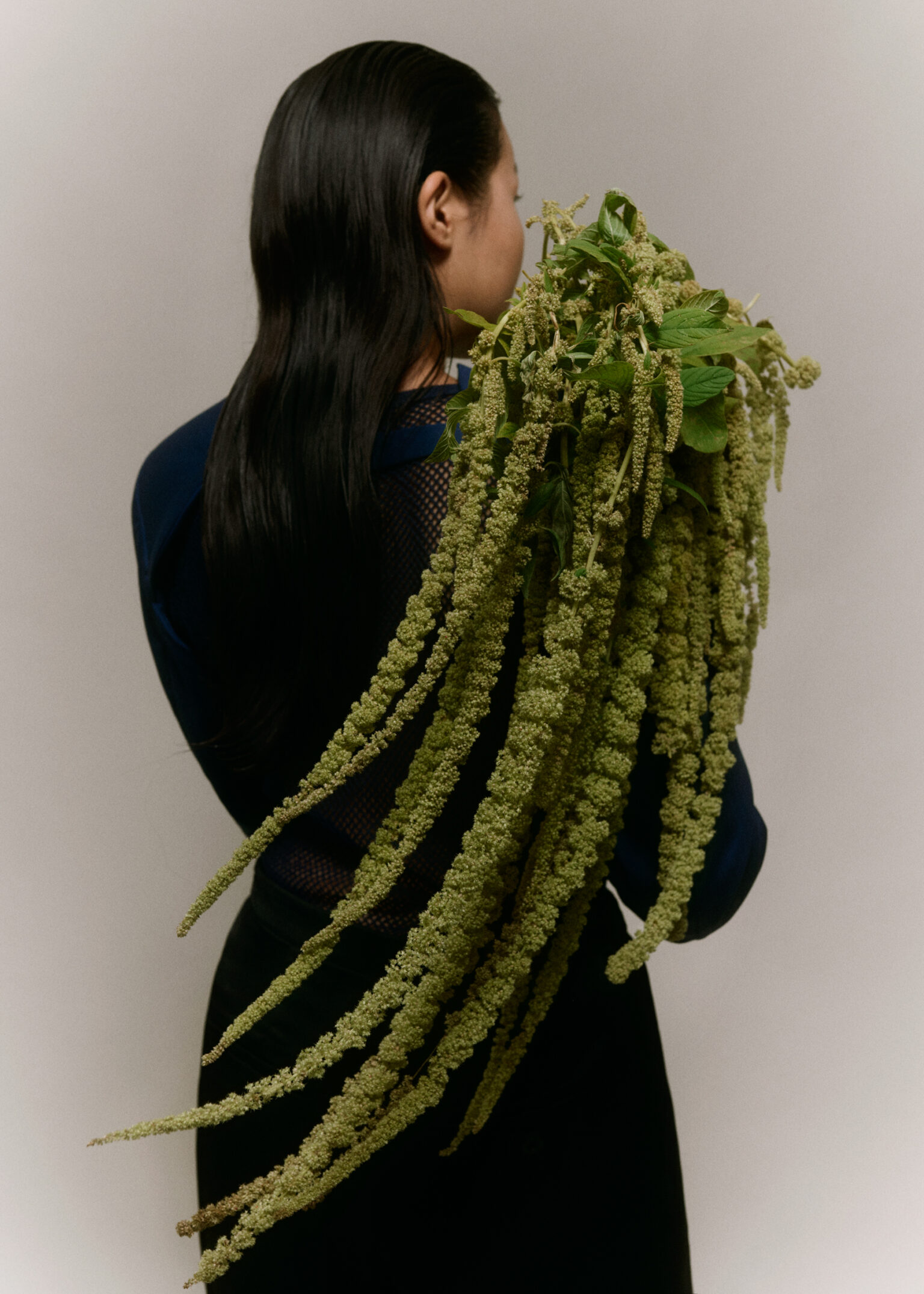 a woman with long black hair and long green leaves