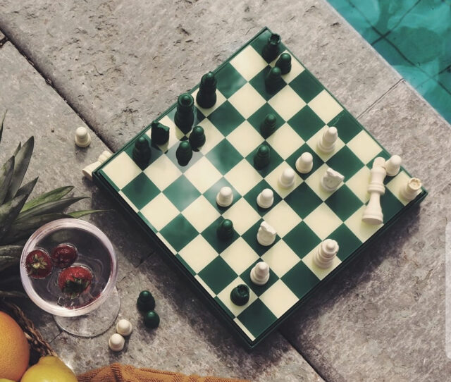 a chess board with chess pieces and a glass of water next to it