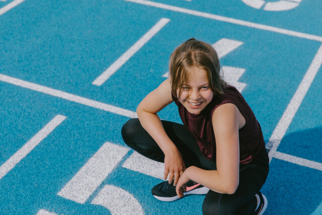 a girl squatting on a blue track