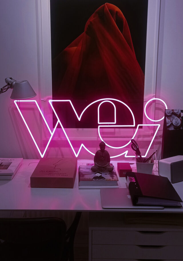 a desk with a pink neon sign