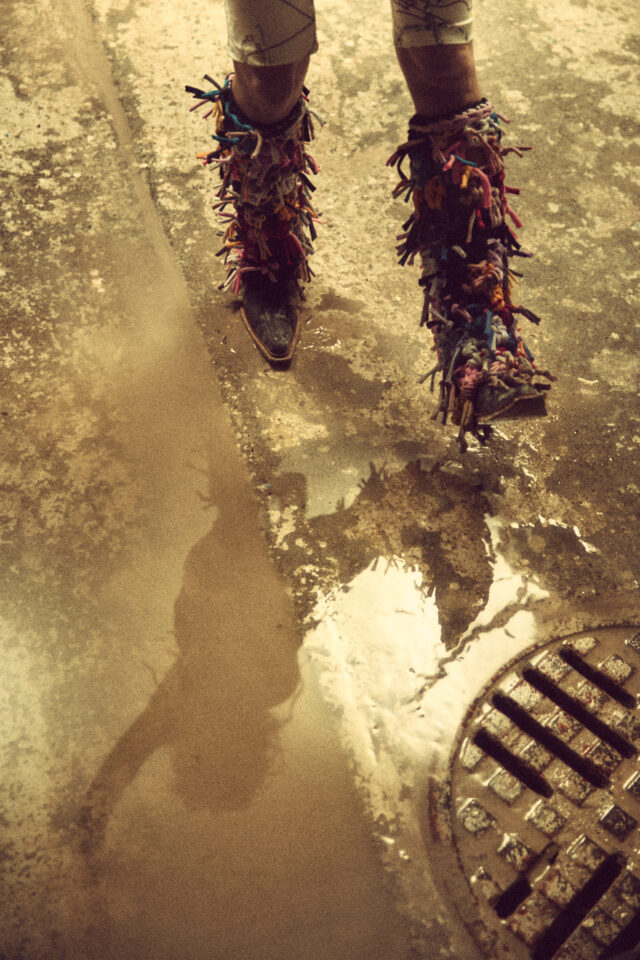 a person wearing fringed boots walking on wet ground