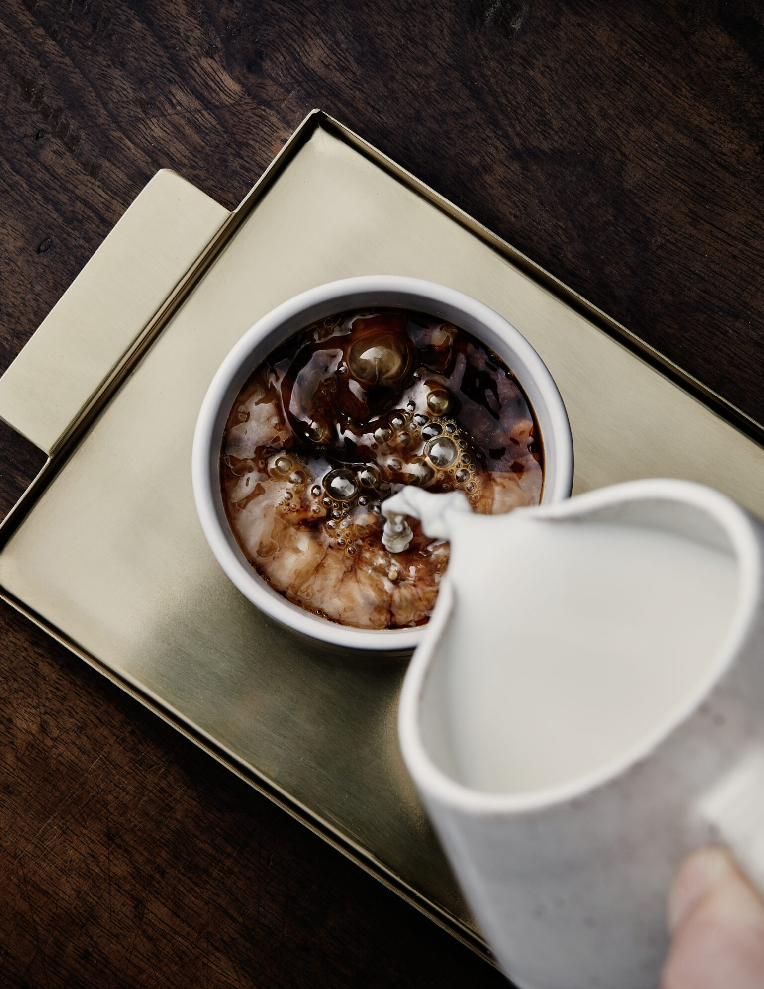 a cup of coffee with a creamer being poured into it
