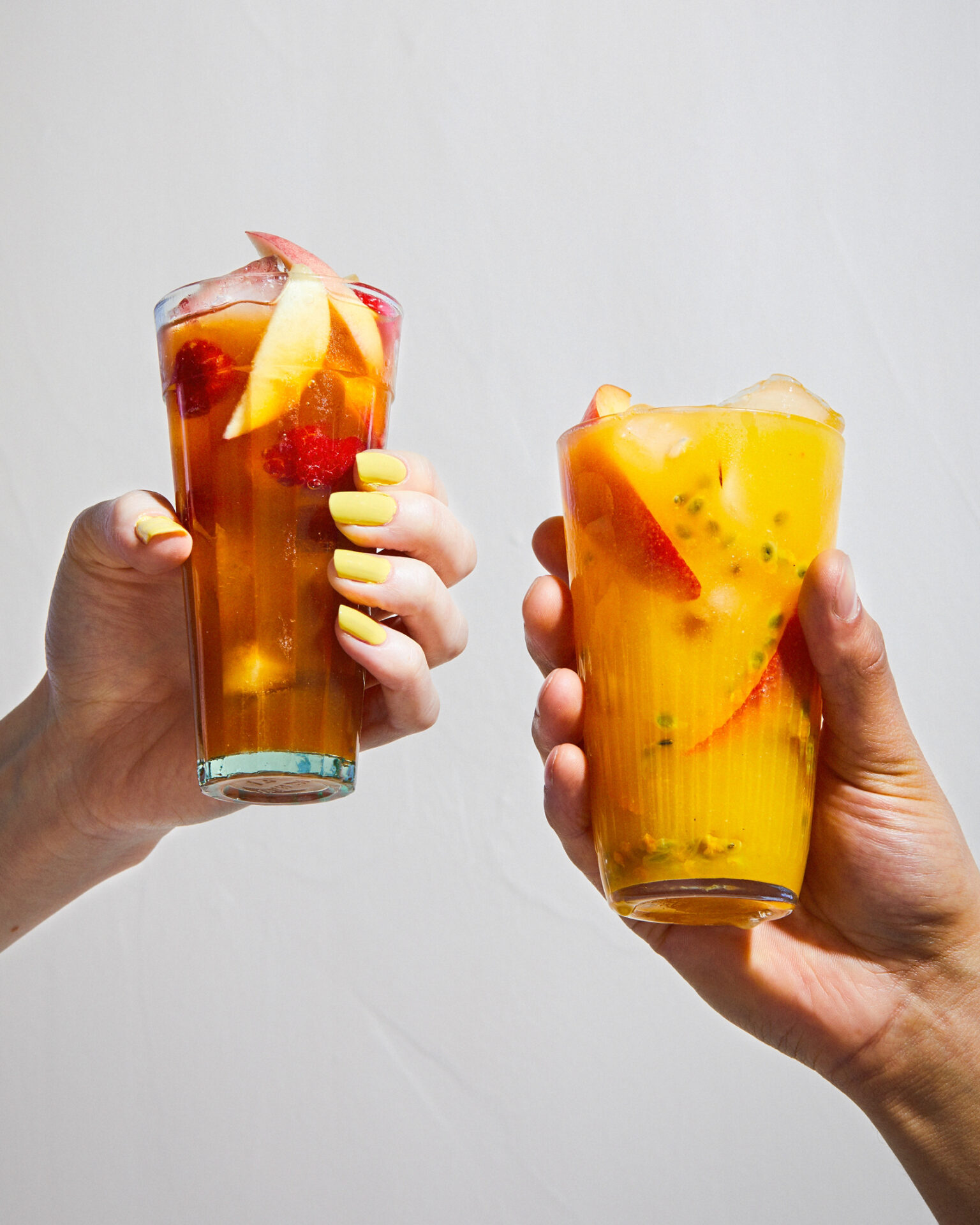 a pair of hands holding glasses of fruit juice