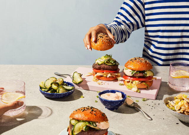 a person putting a bun over a burger