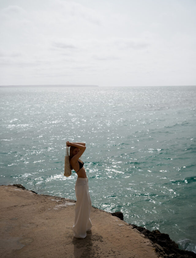 a woman standing on a rock by the water