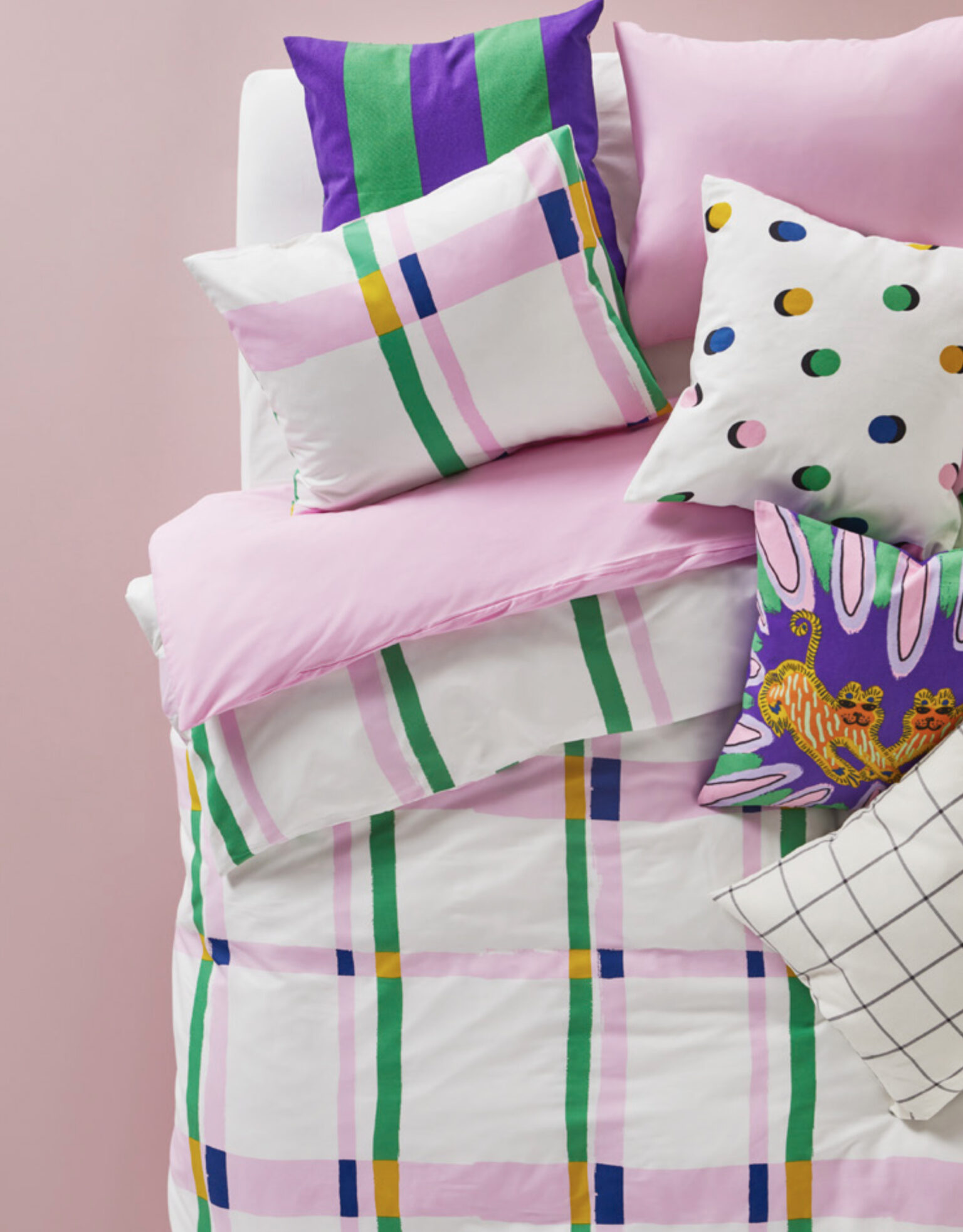 a bed with colorful pillows and checkered duvet