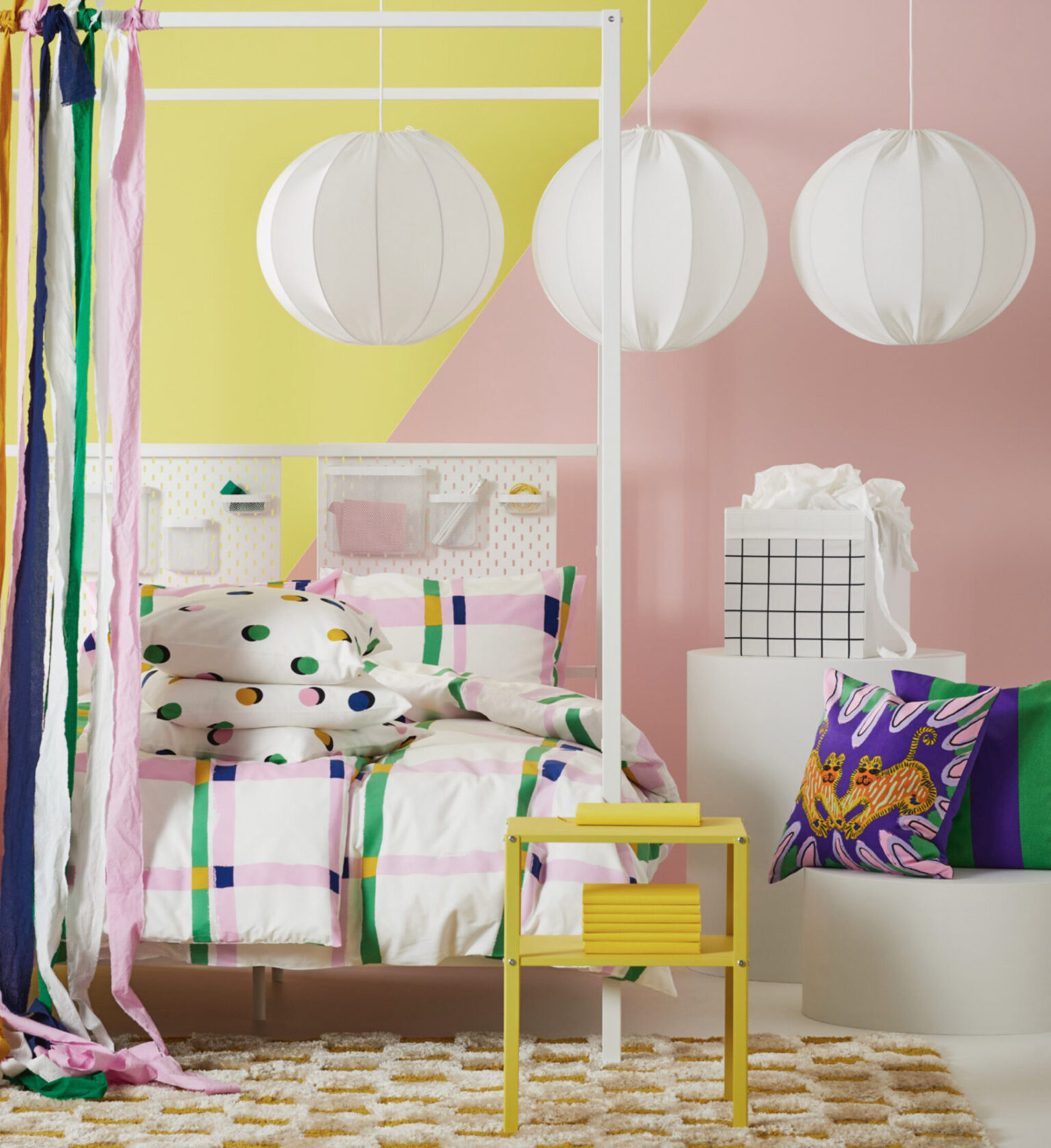 a bed with colorful pillows and a white canopy over a pink and yellow wall