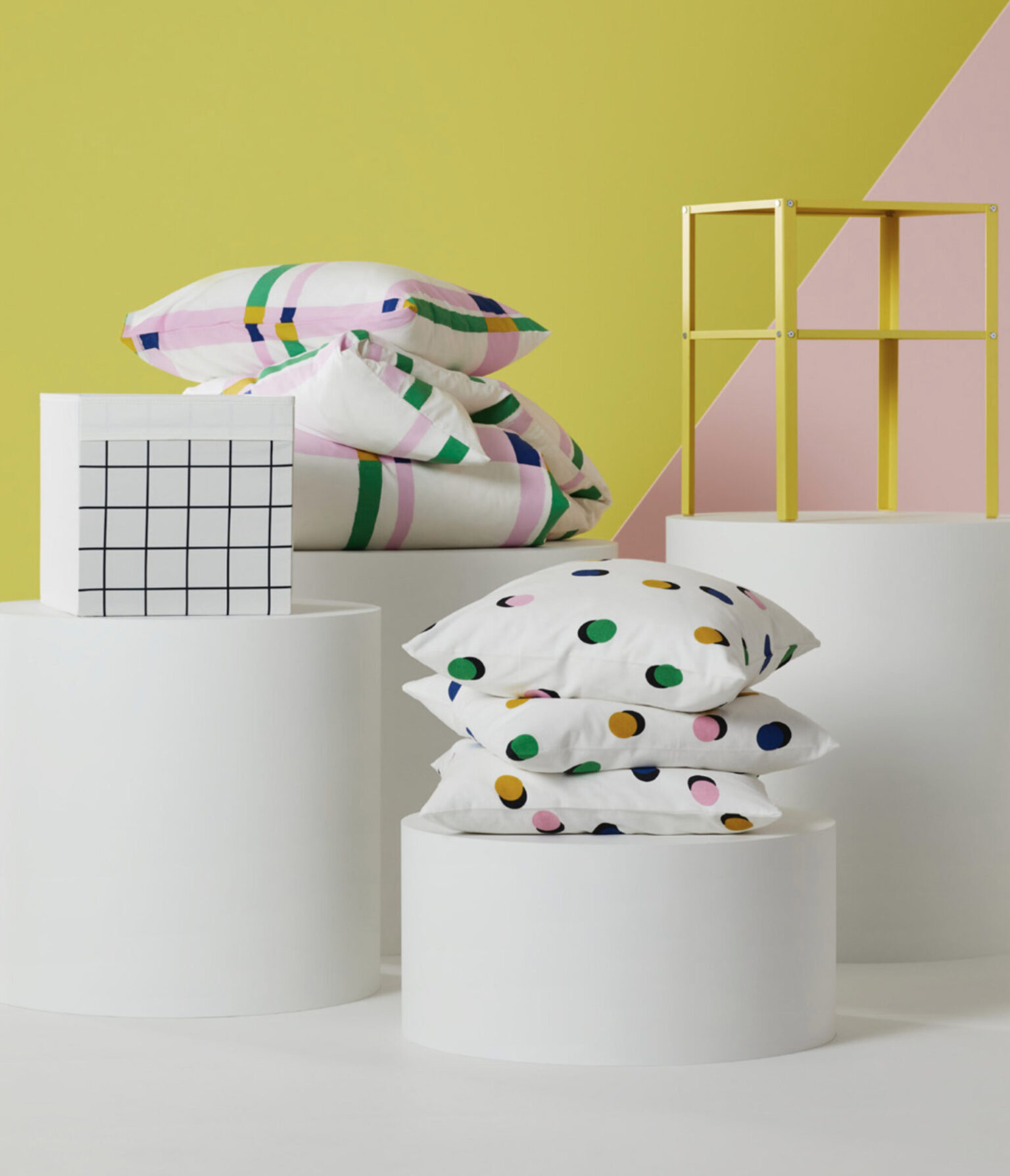 a group of white cylinder boxes with pillows and a yellow and pink background
