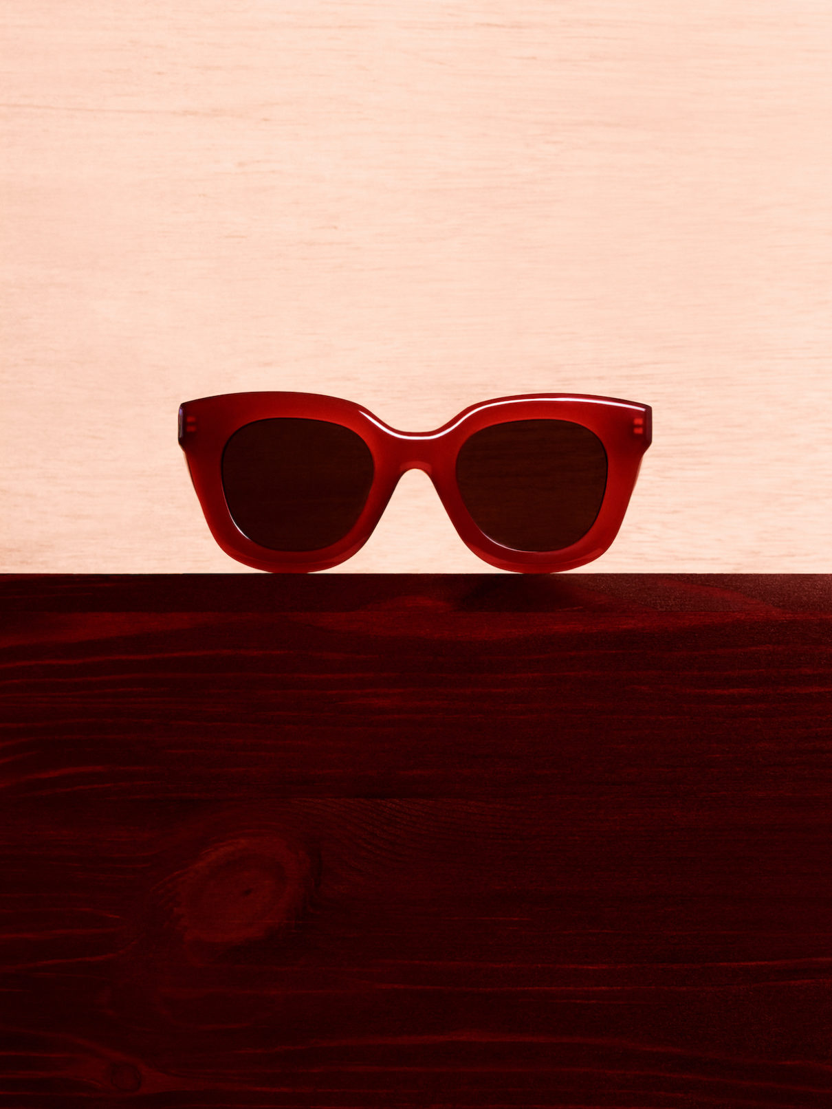 a red sunglasses on a wooden surface