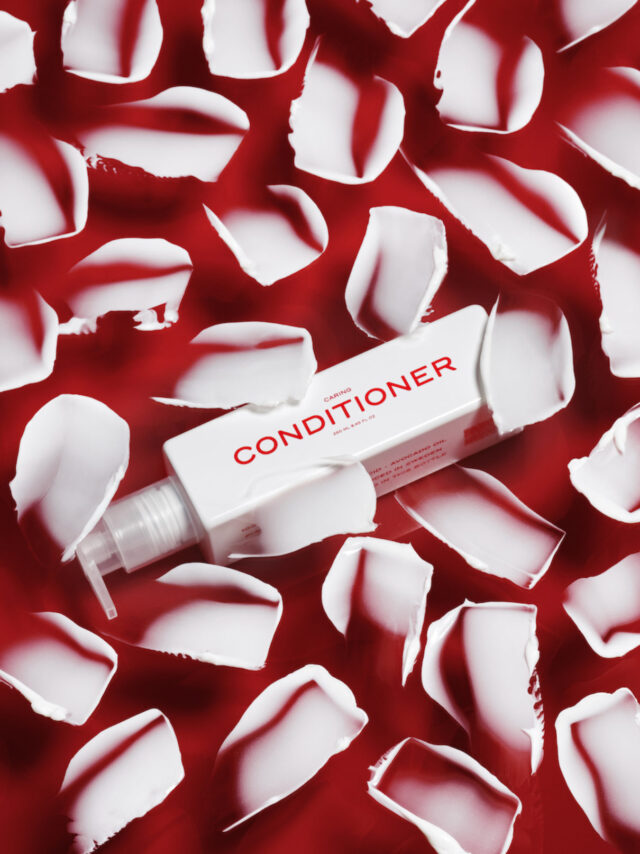 White conditioner bottle surrounded by red background and white cream strokes.