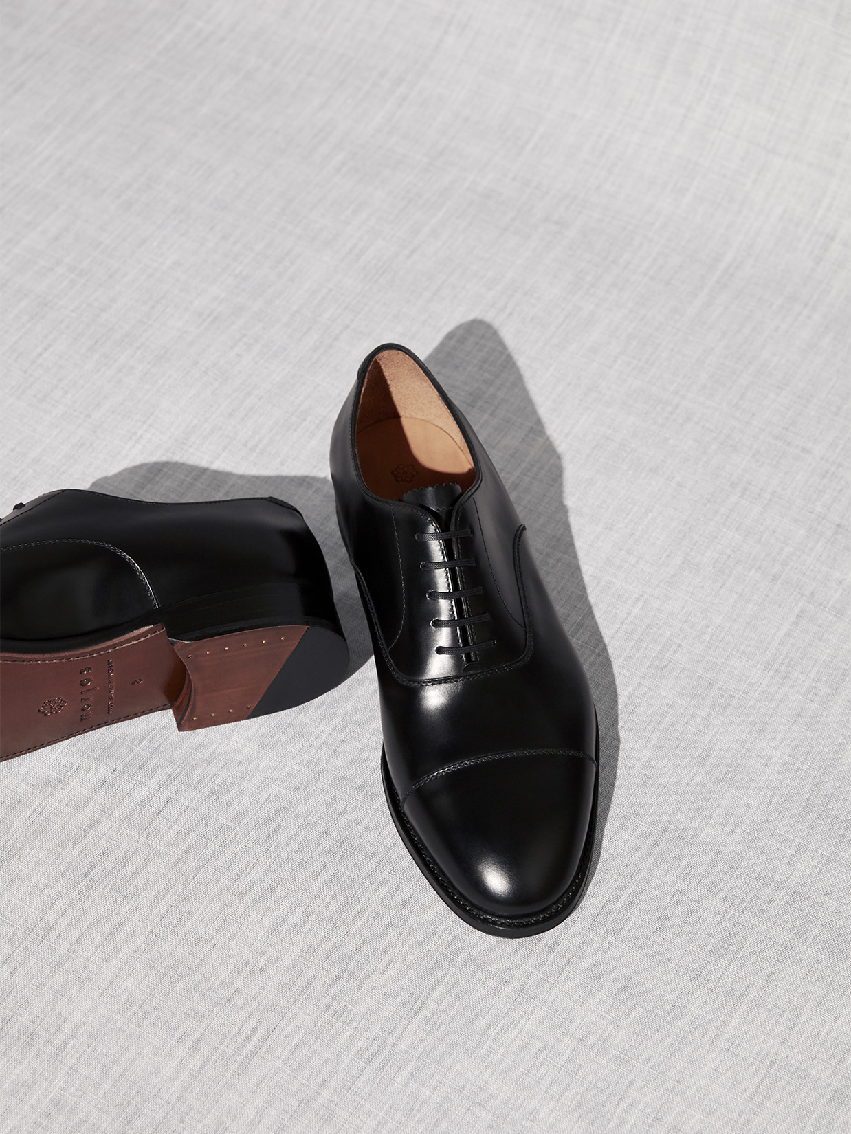A pair of black leather oxford shoes on a textured gray surface.