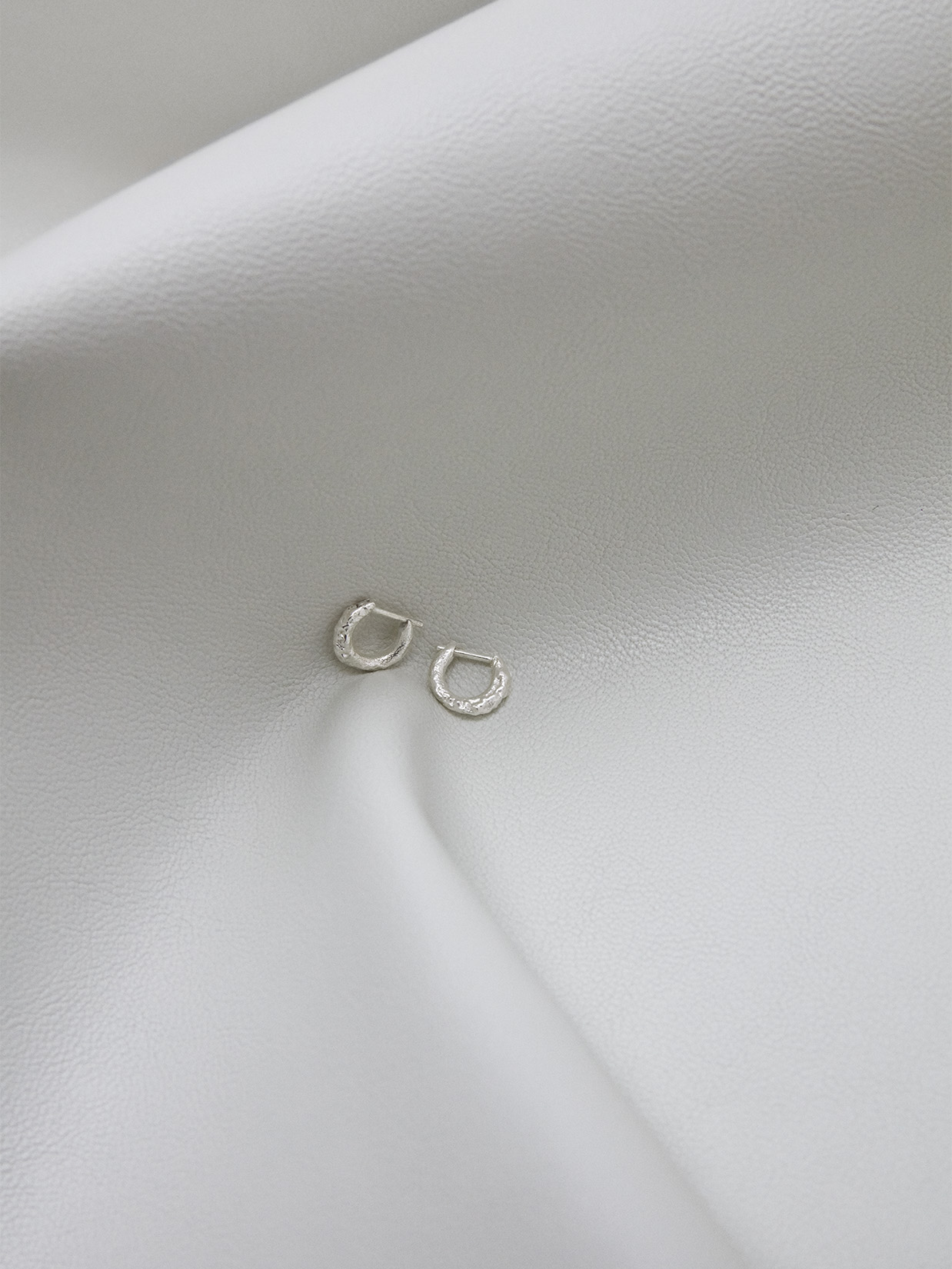 a pair of silver earrings on a white surface