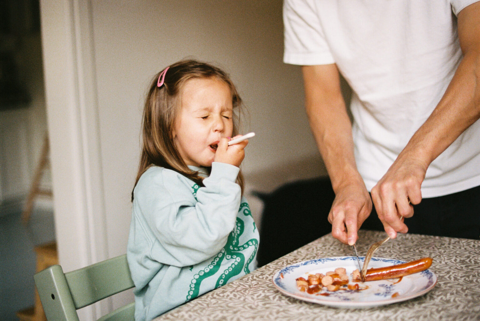 a child eating sausages at a table