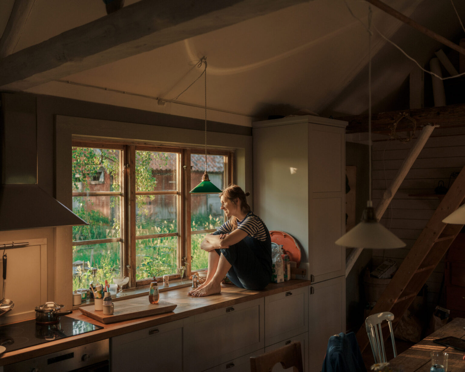 a woman sitting on a countertop looking out a window