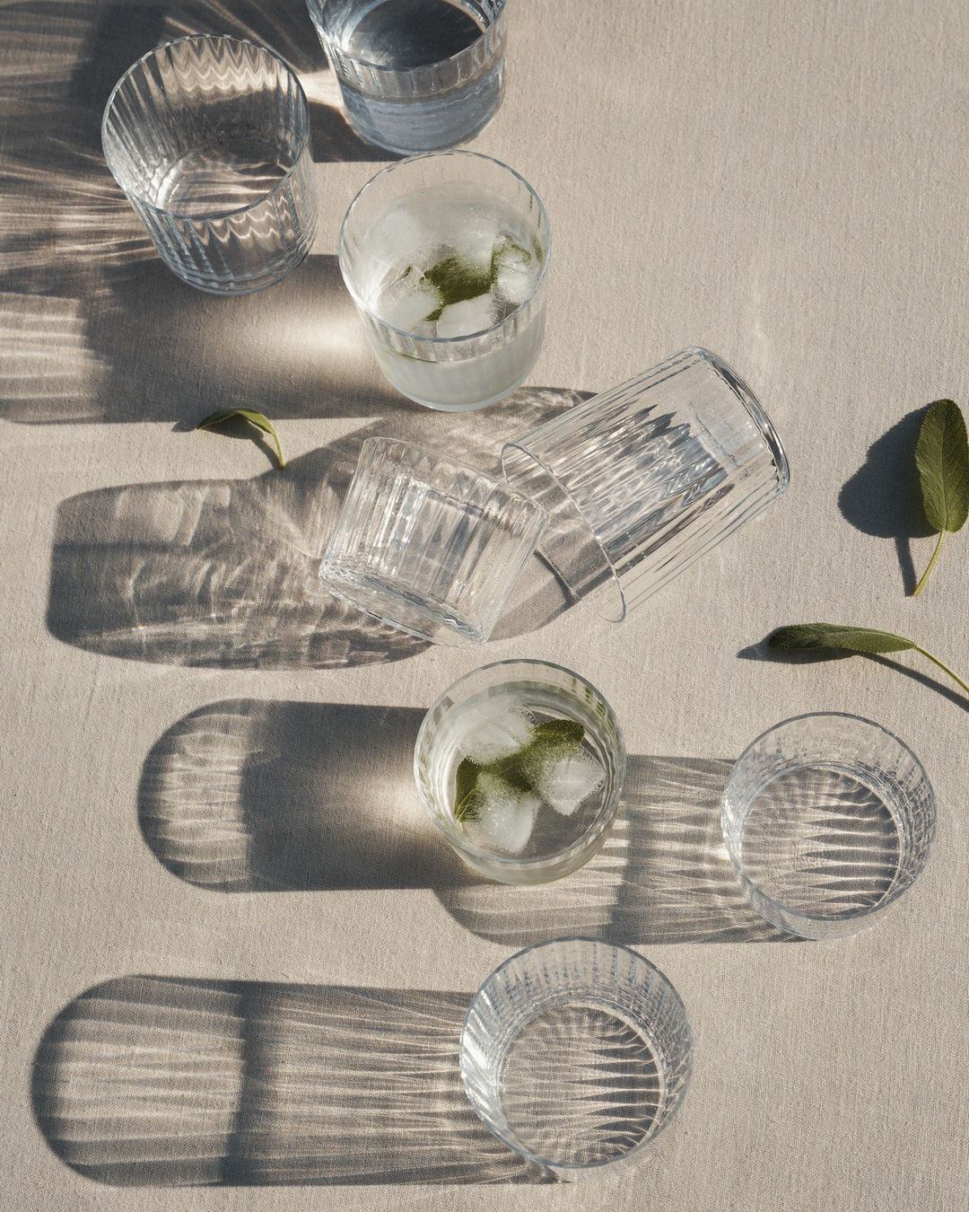a group of glasses with ice and water on a table