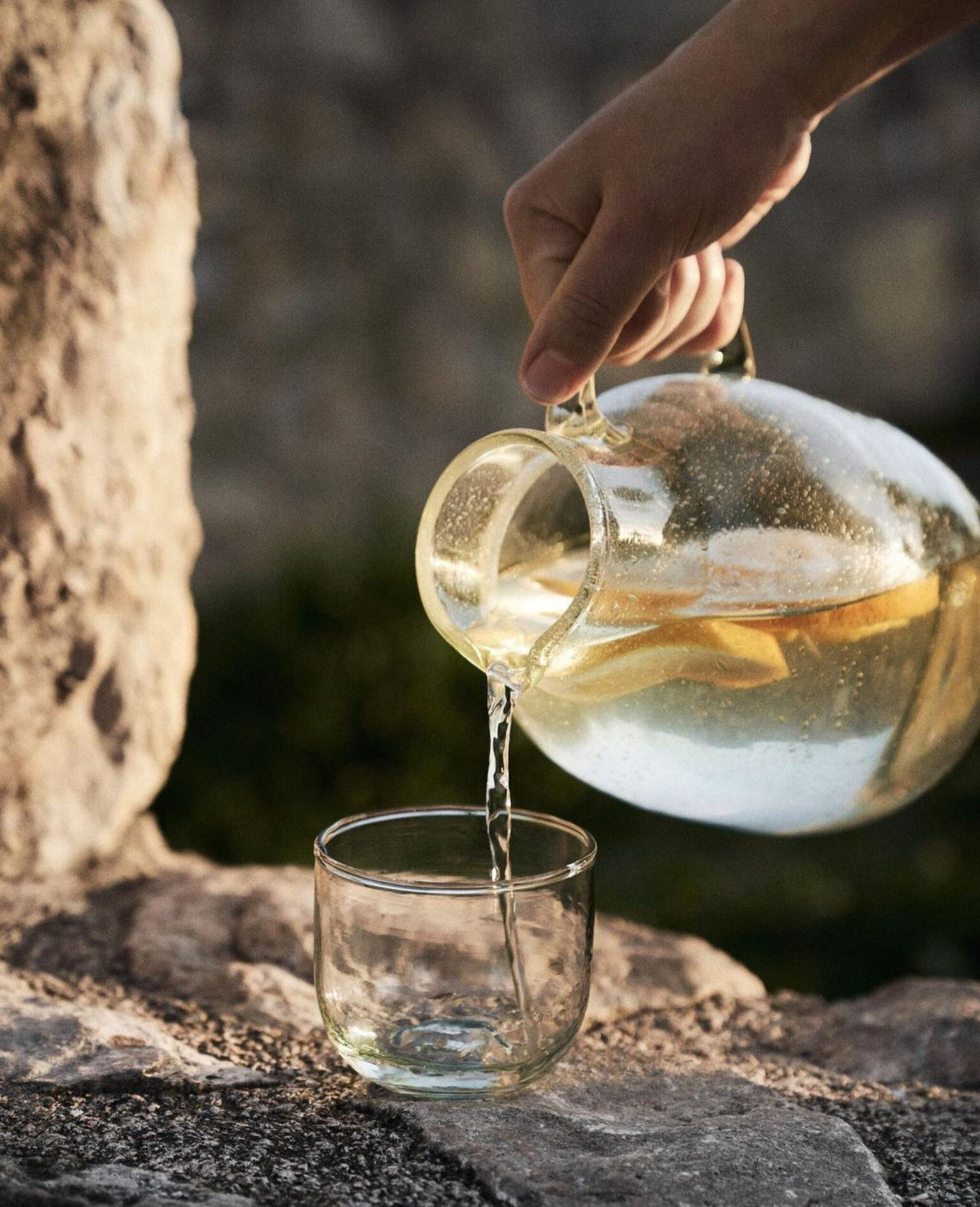 a hand pouring liquid into a glass cup