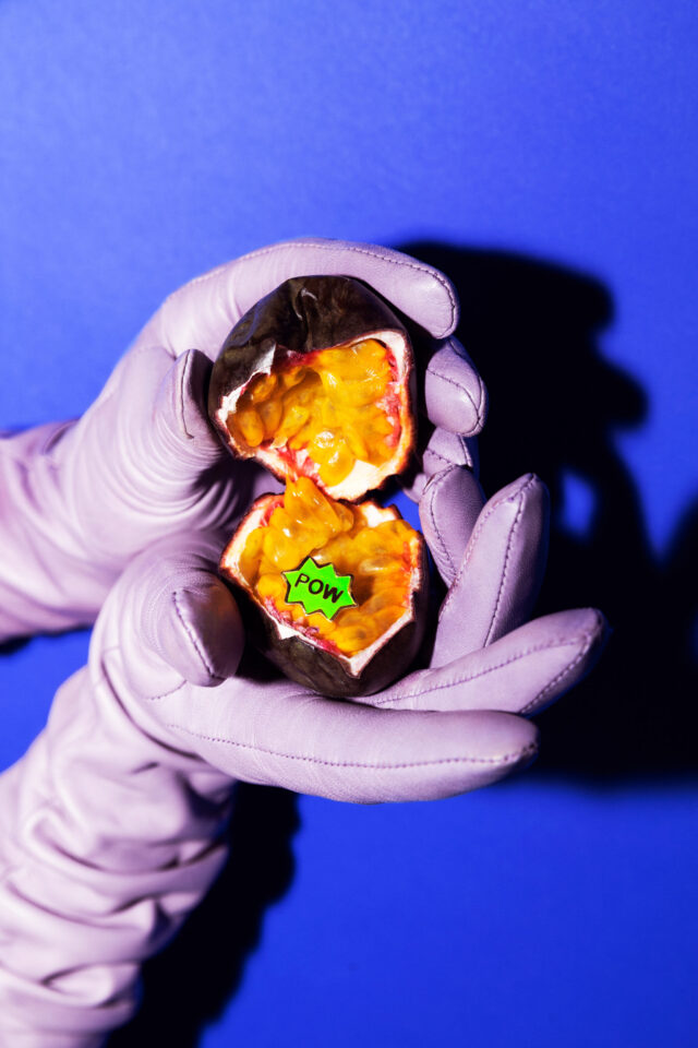 a hand in gloves holding a fruit