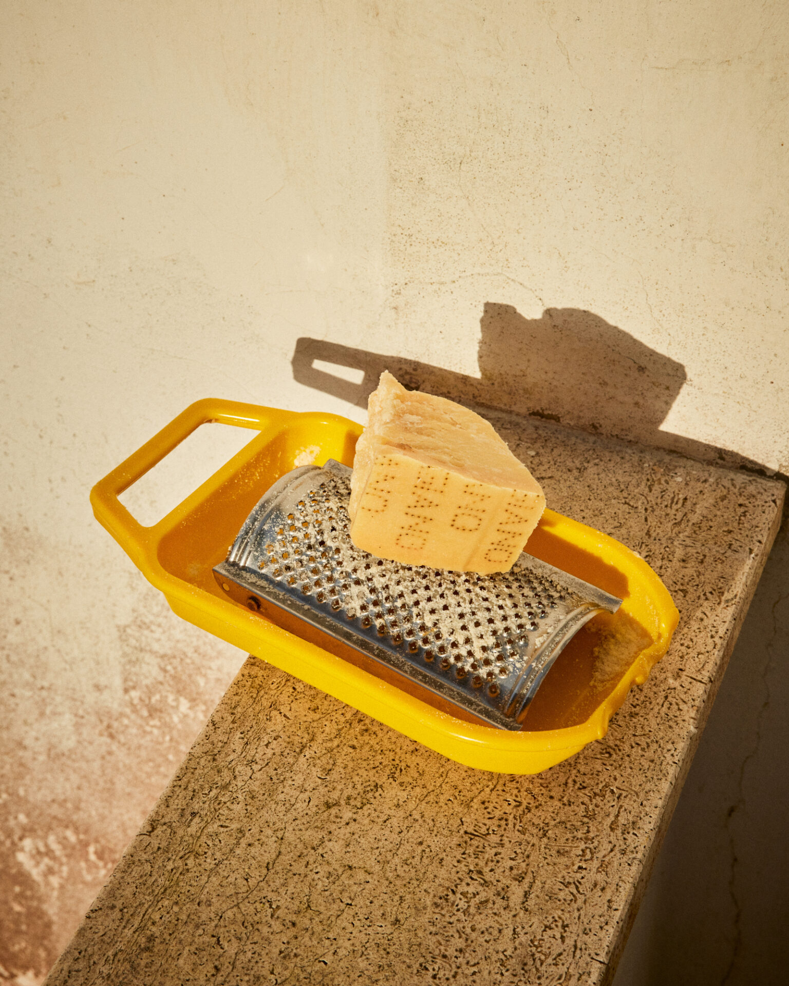 a cheese grater and a piece of cheese on a yellow tray