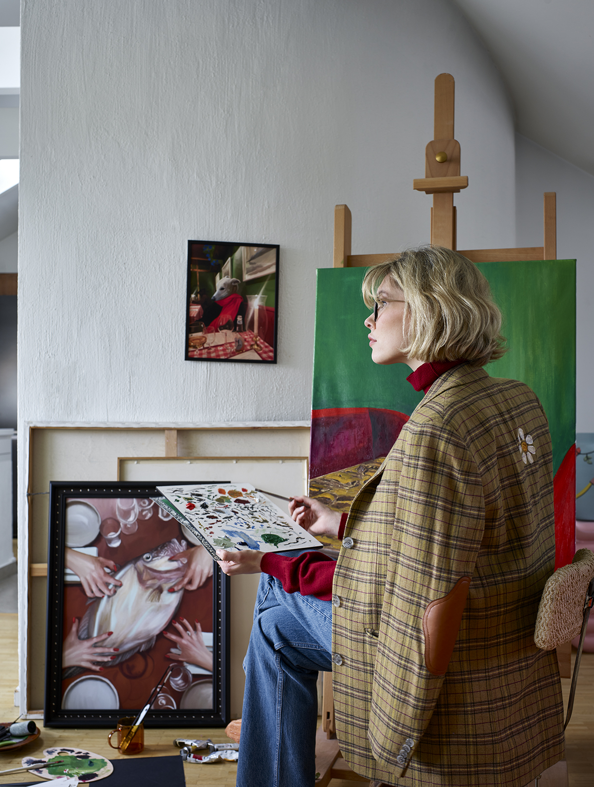 a woman sitting at a table holding a painting