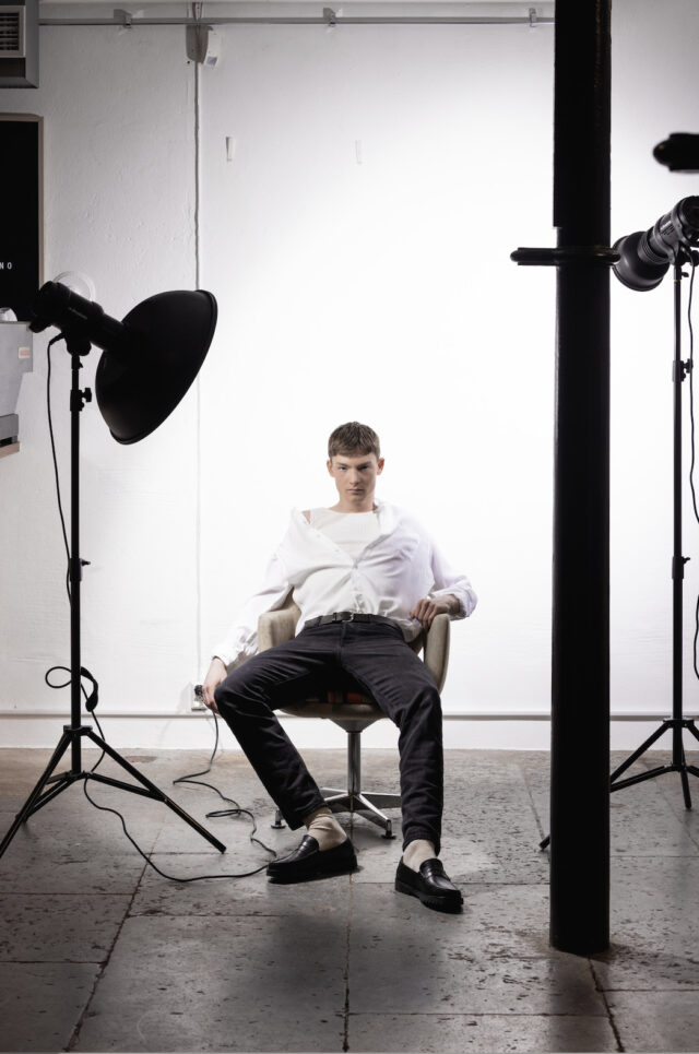 a man sitting in a chair in a photo studio